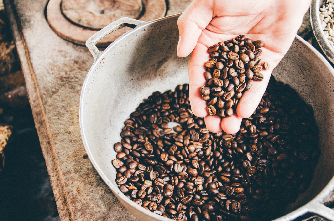 Mano sosteniendo granos de café sobre el tostador